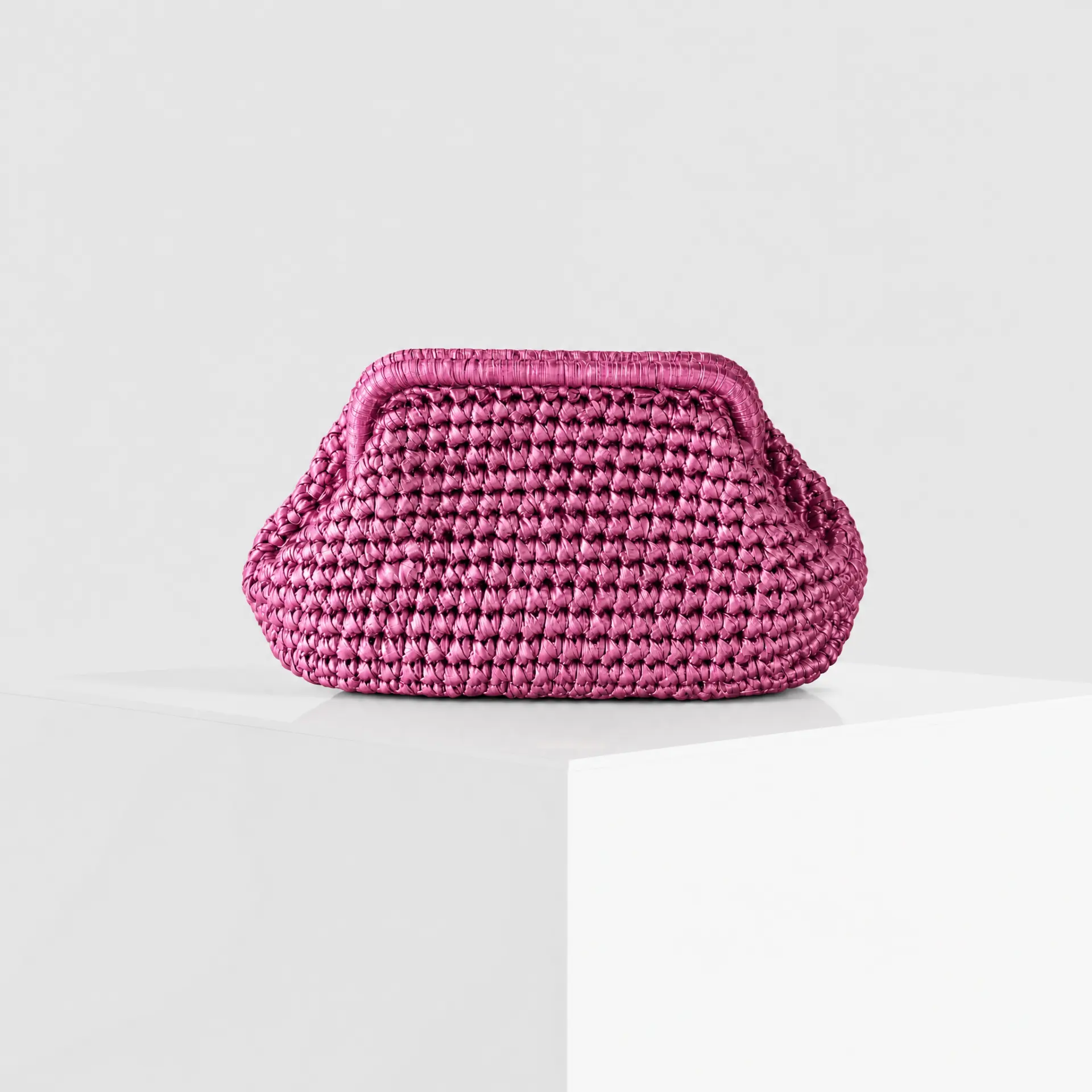 Hand-crocheted raffia cloud clutch in metallic fuchsia pink