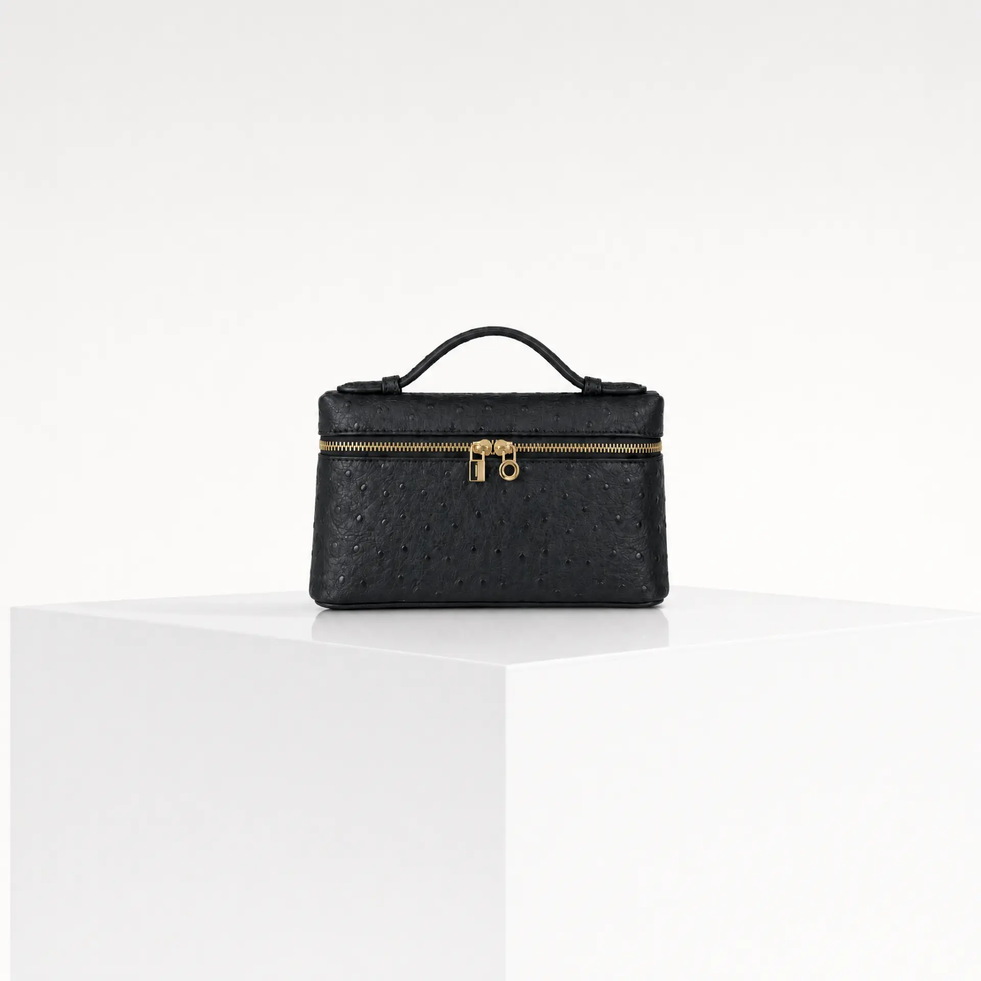 Black ostrich-embossed top-handle mini case bag with gold wrap-around zipper